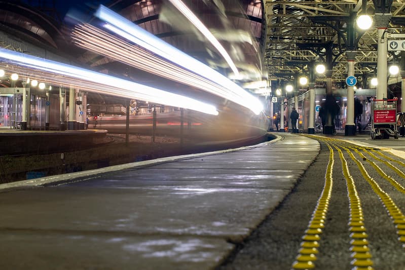 Night railway platform with light trails